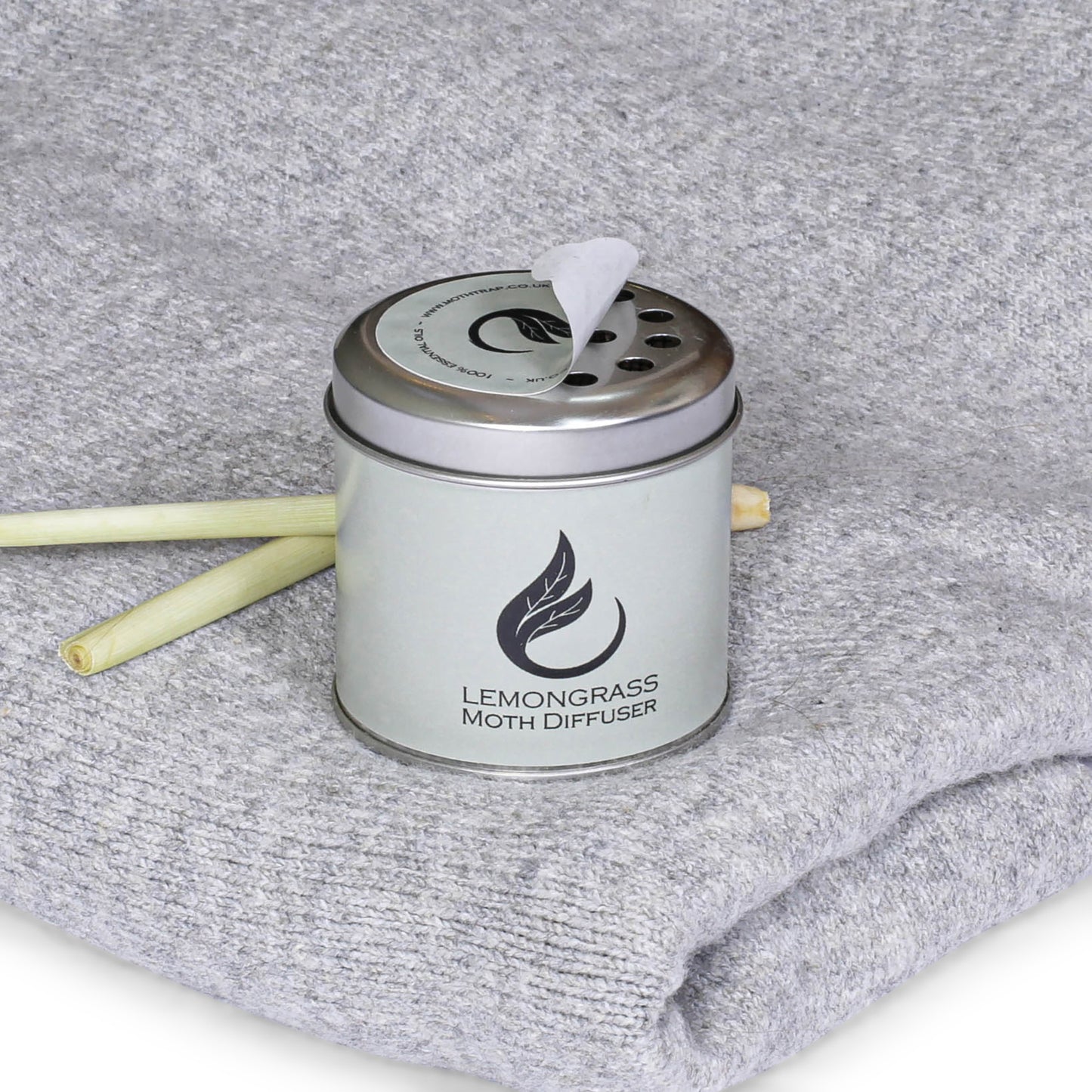 lemongrass moth repellent diffuser tin with lemongrass plant on a grey sweater